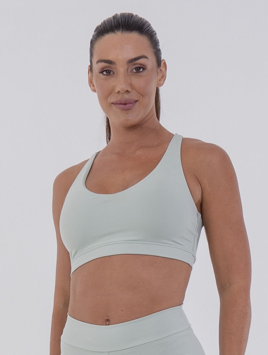 Top fitness verde Aloe com alças cruzadas nas costas, confeccionado em malha tecnológica com toque gelado e proteção UV 50+. Modelagem anatômica e elástico embutido no sub-busto para sustentação e conforto.