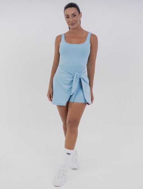 Vestido macaquinho azul Azzure com short interno e saia sobreposta, amarração lateral ajustável e tecido com toque gelado e proteção UV 50+. Ideal para esportes como beach tennis e momentos de lazer.