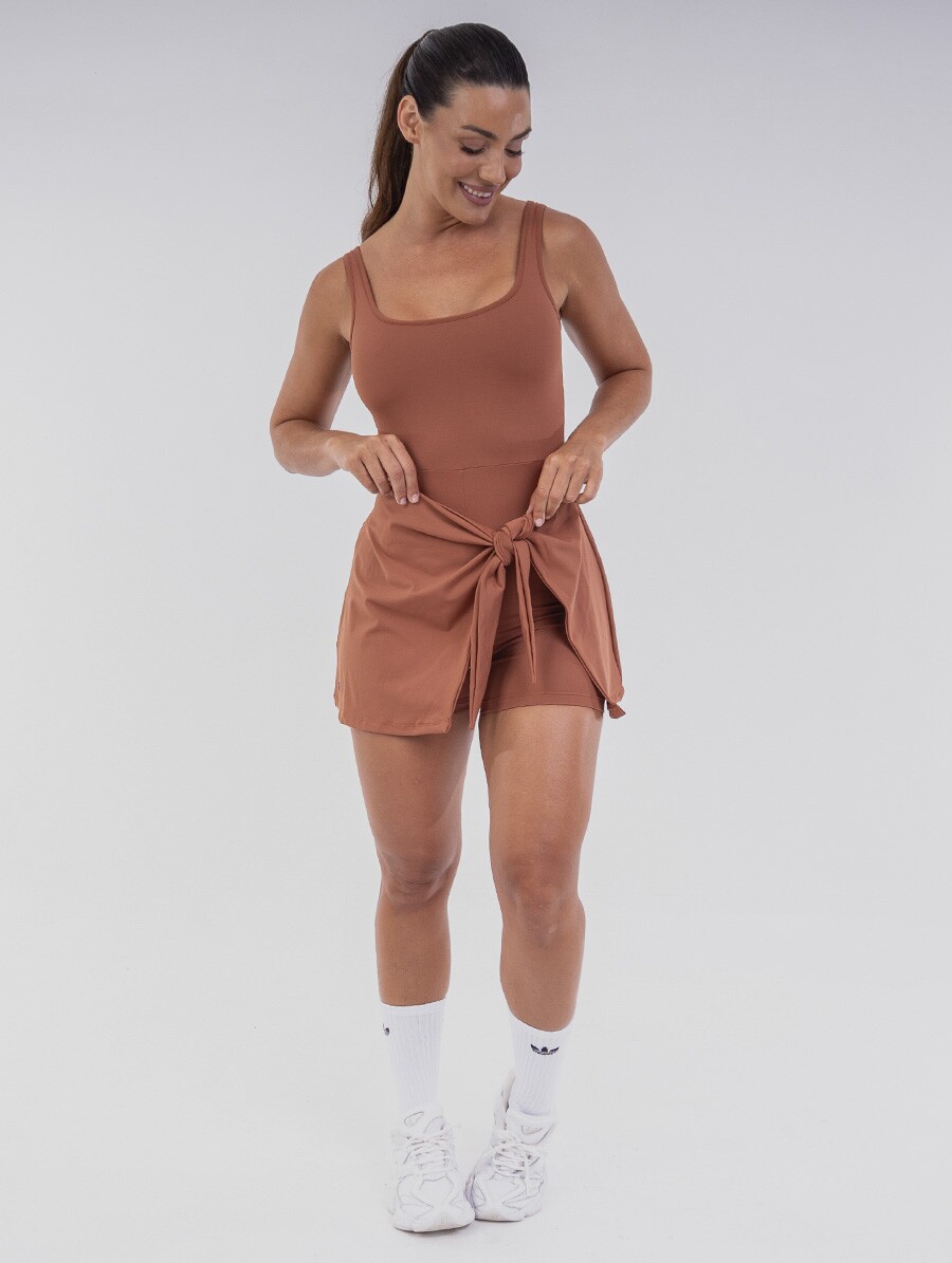 vestido-fitness-marrom Vestido Macaquinho Terracota Belles Active com amarração frontal, short interno e Proteção UV 50+.